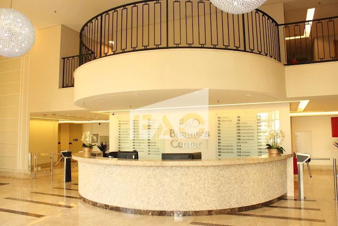 Recepção do edifício comercial onde fica a Clínica JF, com balcão circular e lustres